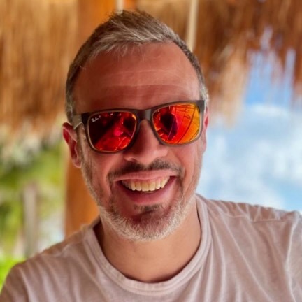 A head-shot photo of Matt White in a tropical location. He is wearing sunglasses.